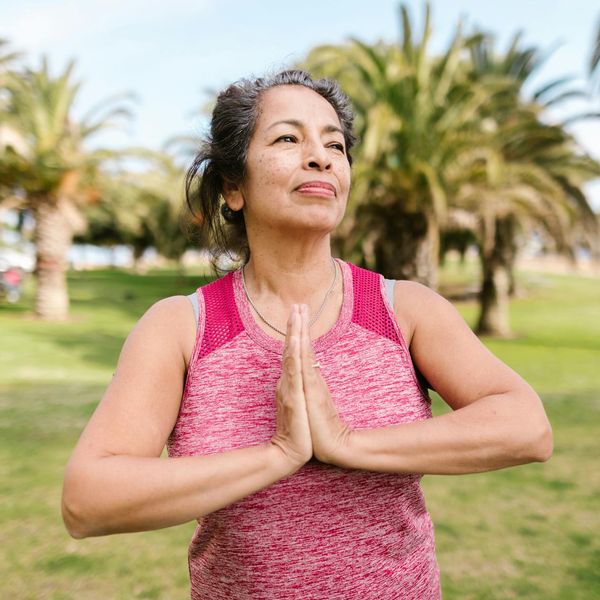 Person smiling and stretching outdoors in a park, feeling energized.